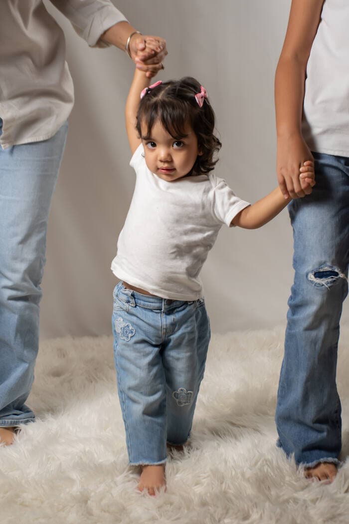 Niña caminando de la mano de sus padres