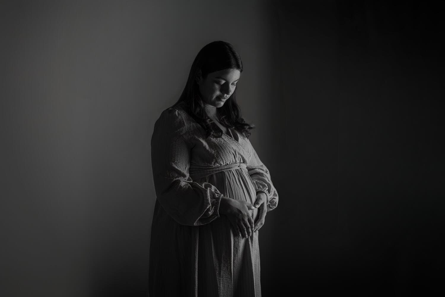 Sesión de maternidad en estudio, una sola luz sobre fondo oscuro